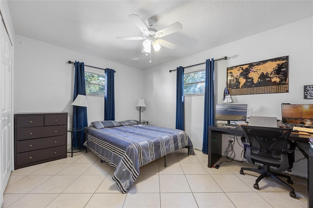 bedroom featuring a textured ceiling, ceiling fan, and light tile patterned flooring