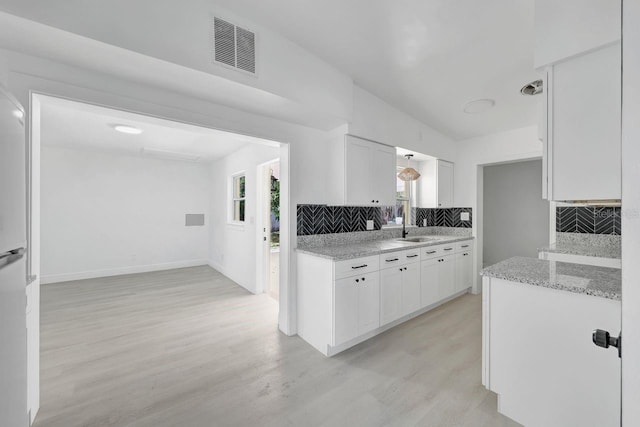 kitchen with white cabinets, tasteful backsplash, a healthy amount of sunlight, and light hardwood / wood-style floors