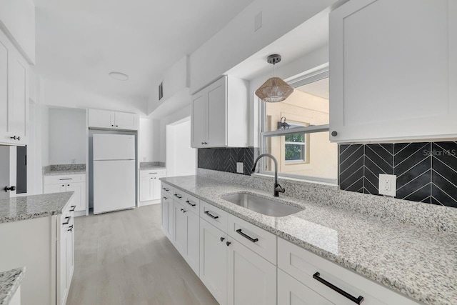 kitchen with decorative backsplash, sink, pendant lighting, white refrigerator, and white cabinets