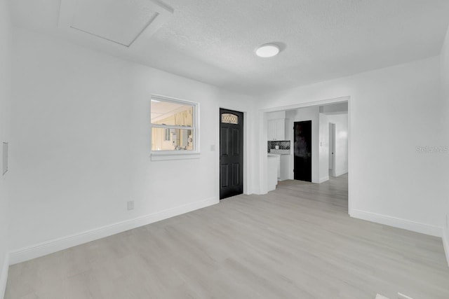 empty room featuring a textured ceiling and light hardwood / wood-style floors