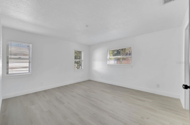 unfurnished room with a textured ceiling and light wood-type flooring