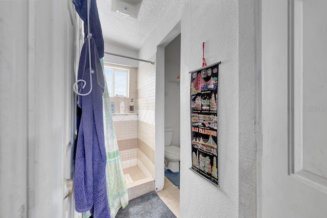 bathroom featuring tile patterned floors, a textured ceiling, toilet, and walk in shower