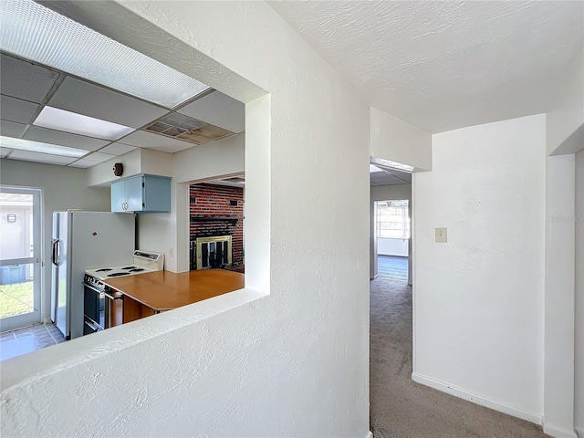 kitchen featuring range with electric cooktop, light colored carpet, a brick fireplace, and a paneled ceiling