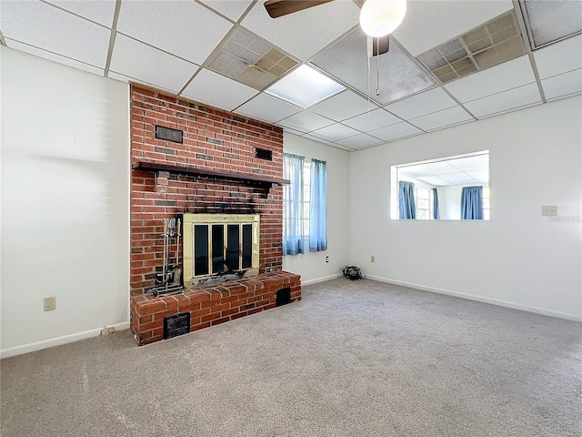 unfurnished living room with a drop ceiling, ceiling fan, carpet floors, and a fireplace