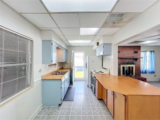 kitchen with a fireplace, a drop ceiling, stainless steel range with electric cooktop, and sink