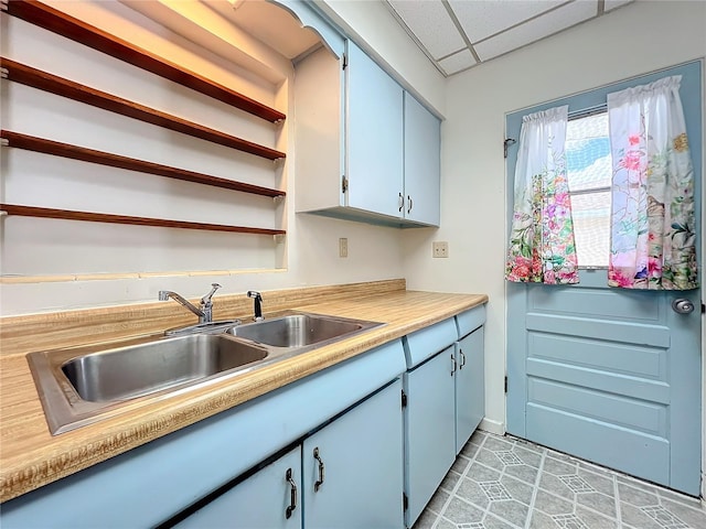 kitchen with a paneled ceiling, light tile patterned floors, and sink