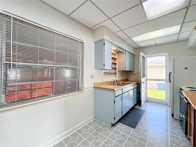 kitchen with a drop ceiling, range with electric stovetop, light tile patterned floors, and sink