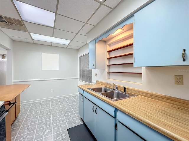 kitchen featuring a paneled ceiling, blue cabinets, and sink