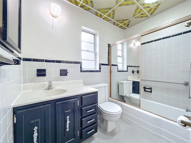 full bathroom with combined bath / shower with glass door, tile patterned floors, vanity, tile walls, and toilet