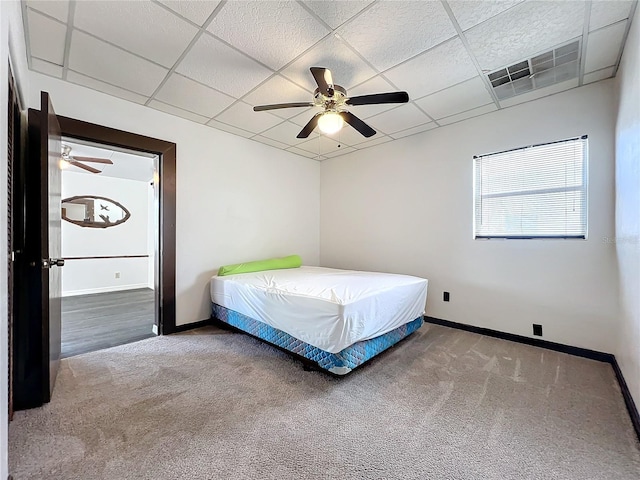 unfurnished bedroom with ceiling fan, a drop ceiling, and carpet floors