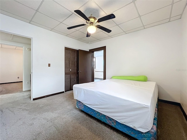 carpeted bedroom featuring a paneled ceiling, ceiling fan, and a closet