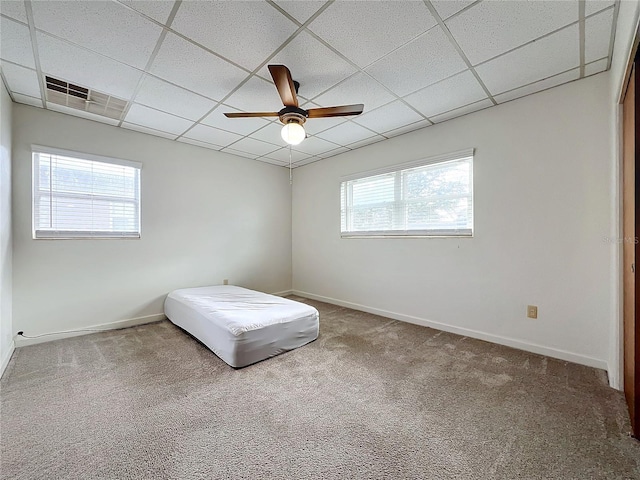 unfurnished bedroom featuring a paneled ceiling, ceiling fan, carpet floors, and multiple windows