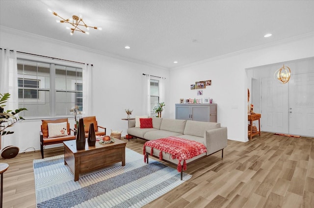 living room featuring light hardwood / wood-style floors, ornamental molding, a textured ceiling, and a chandelier