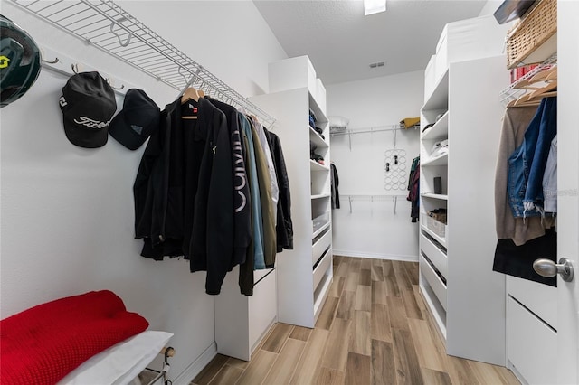 walk in closet with light hardwood / wood-style floors