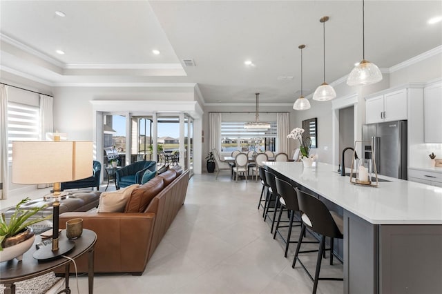 kitchen featuring white cabinets, a spacious island, crown molding, high quality fridge, and decorative light fixtures