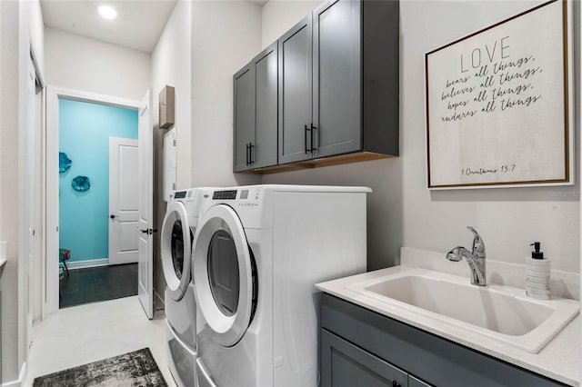 clothes washing area with washing machine and dryer, sink, light tile patterned flooring, and cabinets