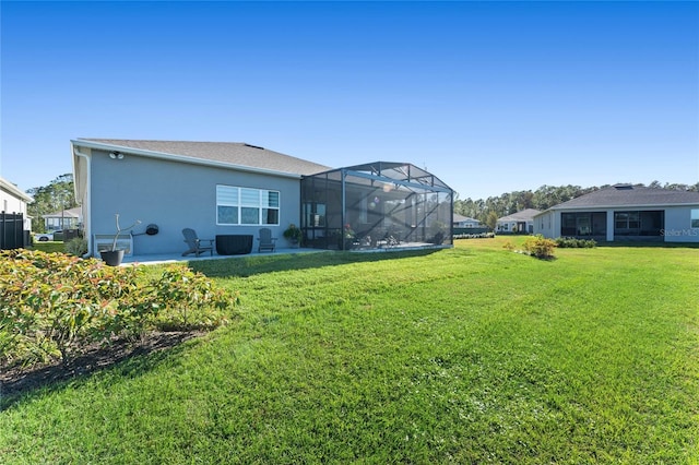 back of house with a lanai, a patio area, and a lawn