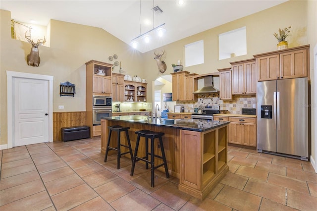 kitchen with wall chimney exhaust hood, high vaulted ceiling, a breakfast bar area, a kitchen island with sink, and appliances with stainless steel finishes