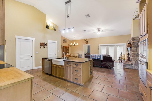 kitchen with pendant lighting, a kitchen island with sink, ceiling fan with notable chandelier, sink, and stainless steel appliances