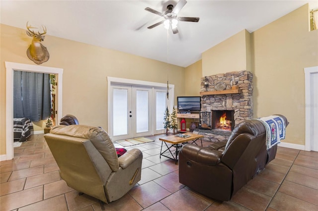 tiled living room with french doors, high vaulted ceiling, a stone fireplace, and ceiling fan