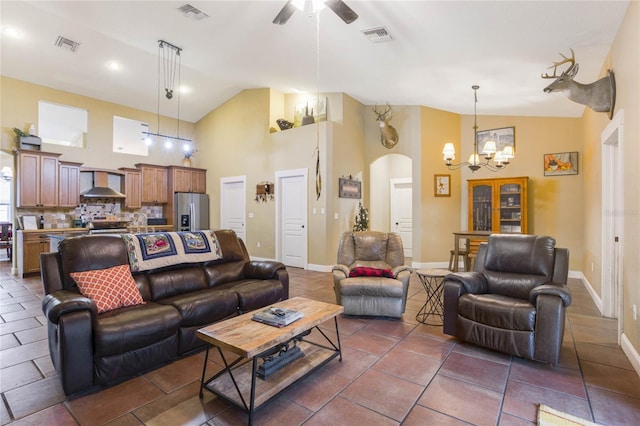 tiled living room featuring ceiling fan with notable chandelier and high vaulted ceiling