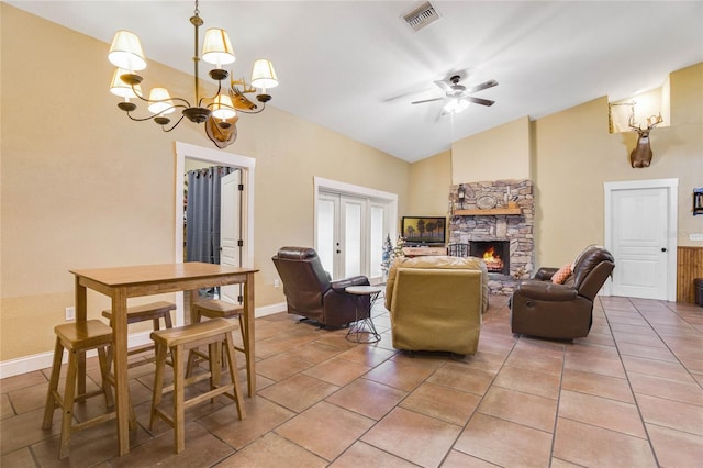 tiled living room with a stone fireplace, lofted ceiling, and ceiling fan with notable chandelier