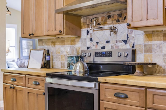 kitchen featuring stainless steel electric stove, backsplash, wooden counters, and range hood