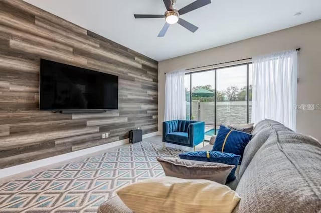 living room with ceiling fan and wood walls