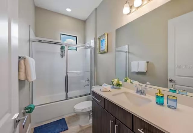 full bathroom featuring vanity, toilet, and bath / shower combo with glass door