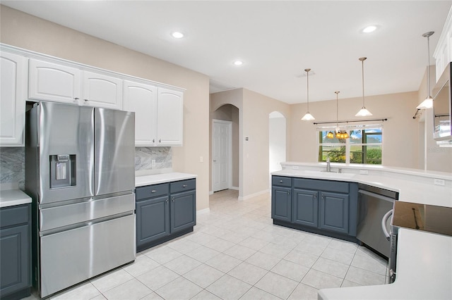 kitchen featuring tasteful backsplash, white cabinets, decorative light fixtures, and appliances with stainless steel finishes