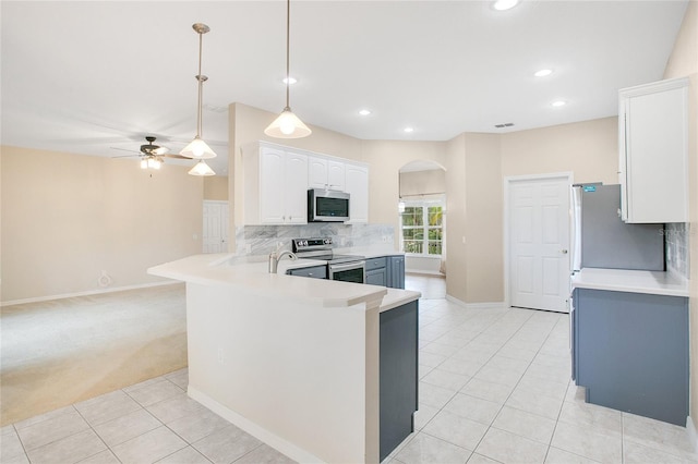 kitchen with pendant lighting, kitchen peninsula, light tile patterned floors, white cabinetry, and stainless steel appliances