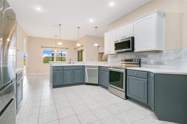 kitchen with sink, white cabinets, stainless steel appliances, and decorative light fixtures