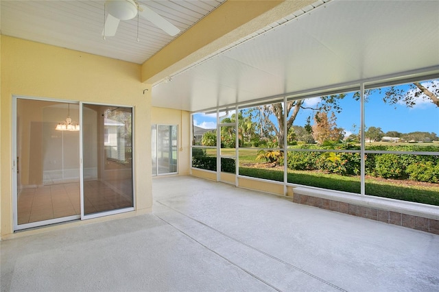 unfurnished sunroom featuring ceiling fan with notable chandelier and beam ceiling