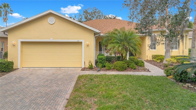 single story home featuring a porch, a garage, and a front yard