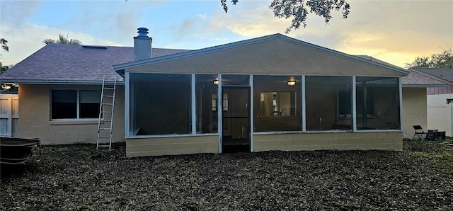 back house at dusk with a sunroom