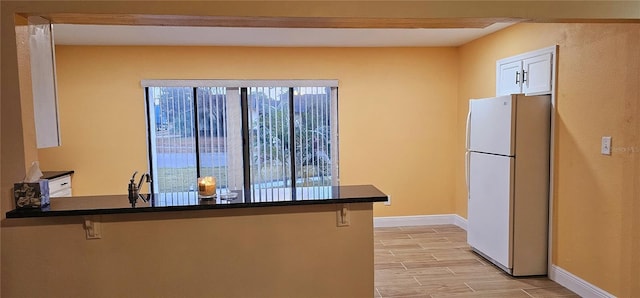 1859 Lake Hill Cir, Orlando, FL 32818 - kitchen with freestanding refrigerator, a breakfast bar, wood finish floors, dark countertops, and a peninsula