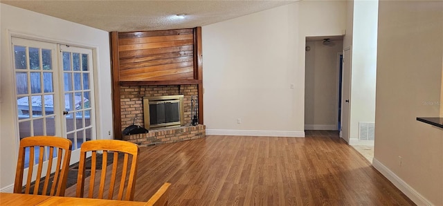 living room featuring hardwood / wood-style floors, a textured ceiling, and a brick fireplace