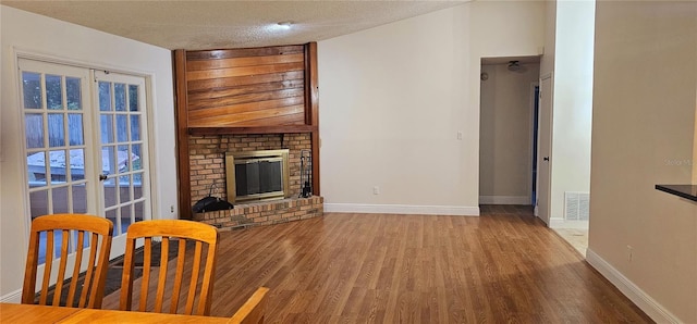 1859 Lake Hill Cir, Orlando, FL 32818 - unfurnished living room with wood finished floors, a brick fireplace, and a textured ceiling
