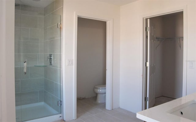 bathroom featuring tile patterned flooring, vanity, toilet, and a shower with shower door