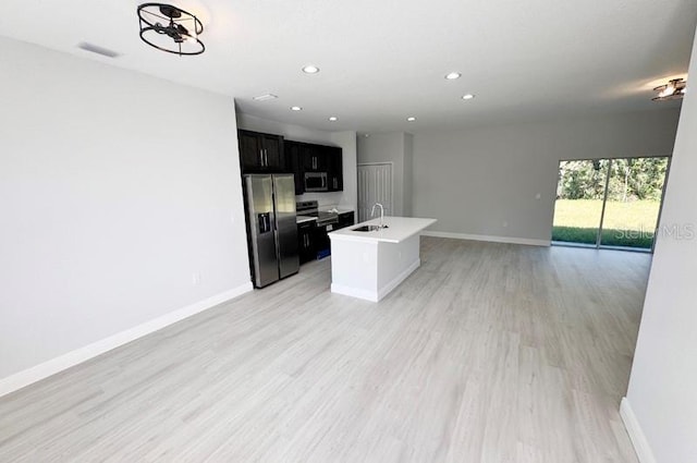 kitchen with a center island with sink, light hardwood / wood-style floors, sink, and stainless steel appliances