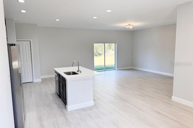 kitchen featuring appliances with stainless steel finishes, an island with sink, light hardwood / wood-style flooring, and sink