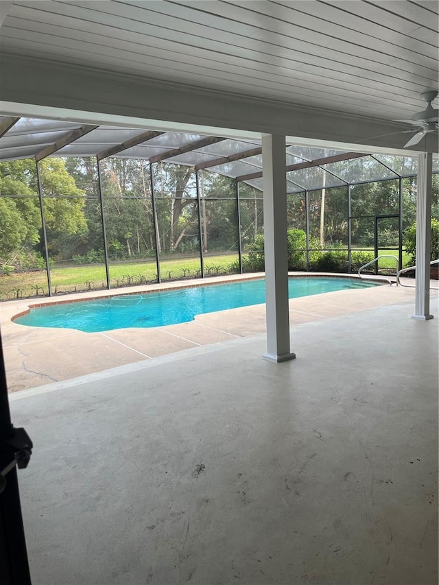 view of pool featuring a patio, glass enclosure, and ceiling fan