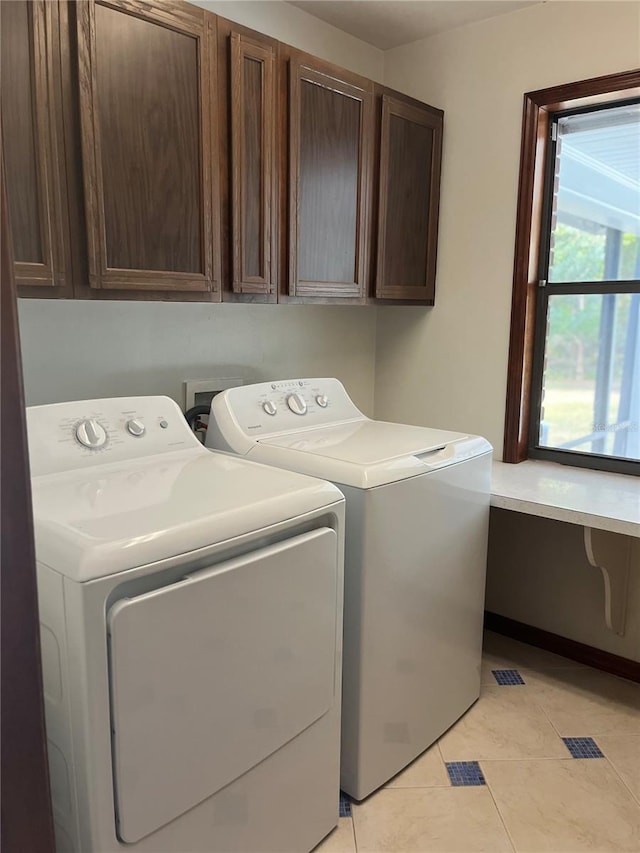 clothes washing area featuring washer and clothes dryer, cabinets, and light tile patterned floors