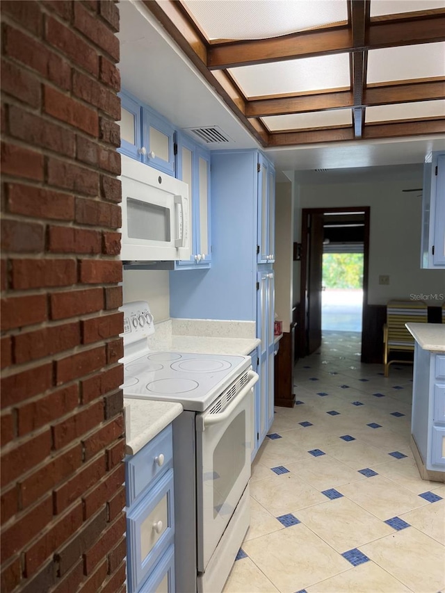 kitchen with beam ceiling, white appliances, blue cabinetry, and light tile patterned floors