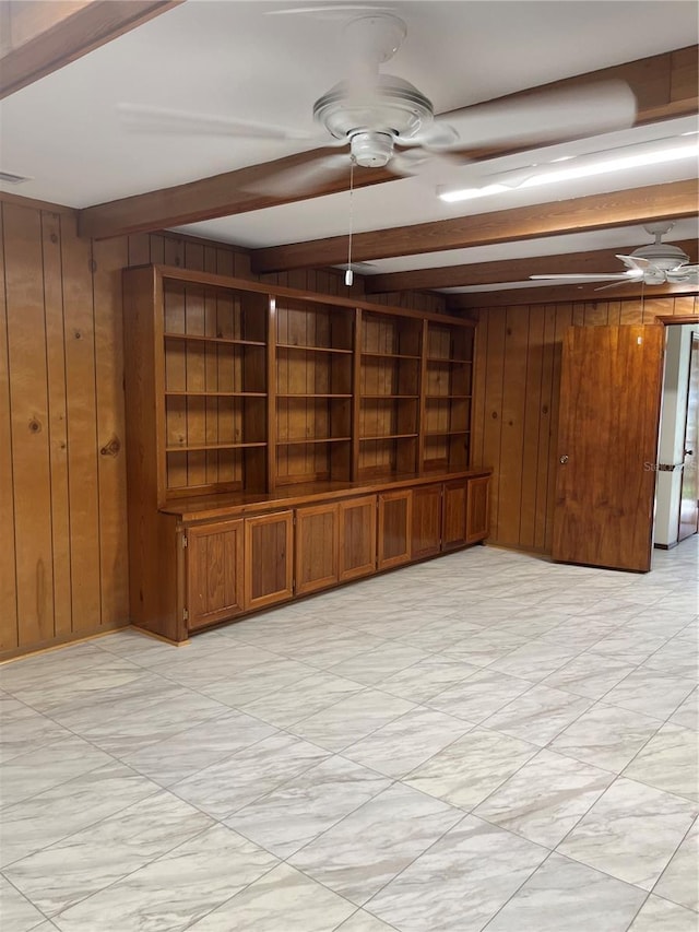 unfurnished living room with beamed ceiling and wood walls