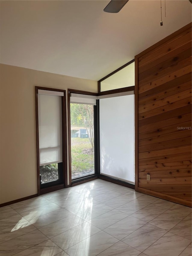 unfurnished room with wood walls and vaulted ceiling