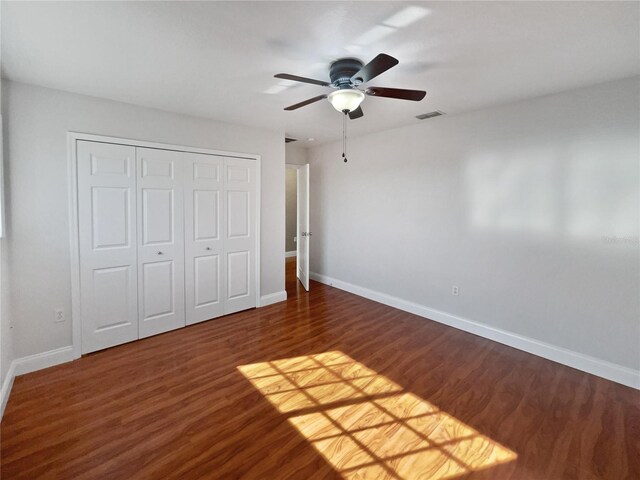 unfurnished bedroom with ceiling fan, dark hardwood / wood-style floors, and a closet