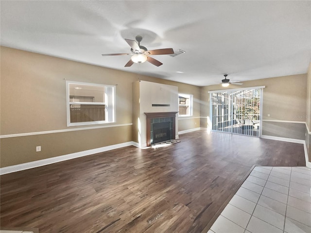 unfurnished living room featuring hardwood / wood-style floors, ceiling fan, and a tile fireplace