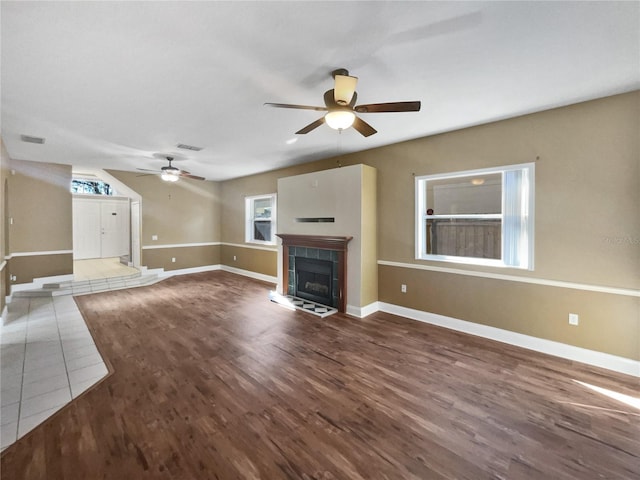 unfurnished living room featuring ceiling fan, a fireplace, and wood-type flooring