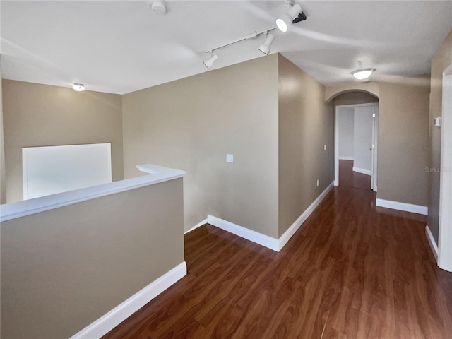 corridor with dark hardwood / wood-style floors and track lighting